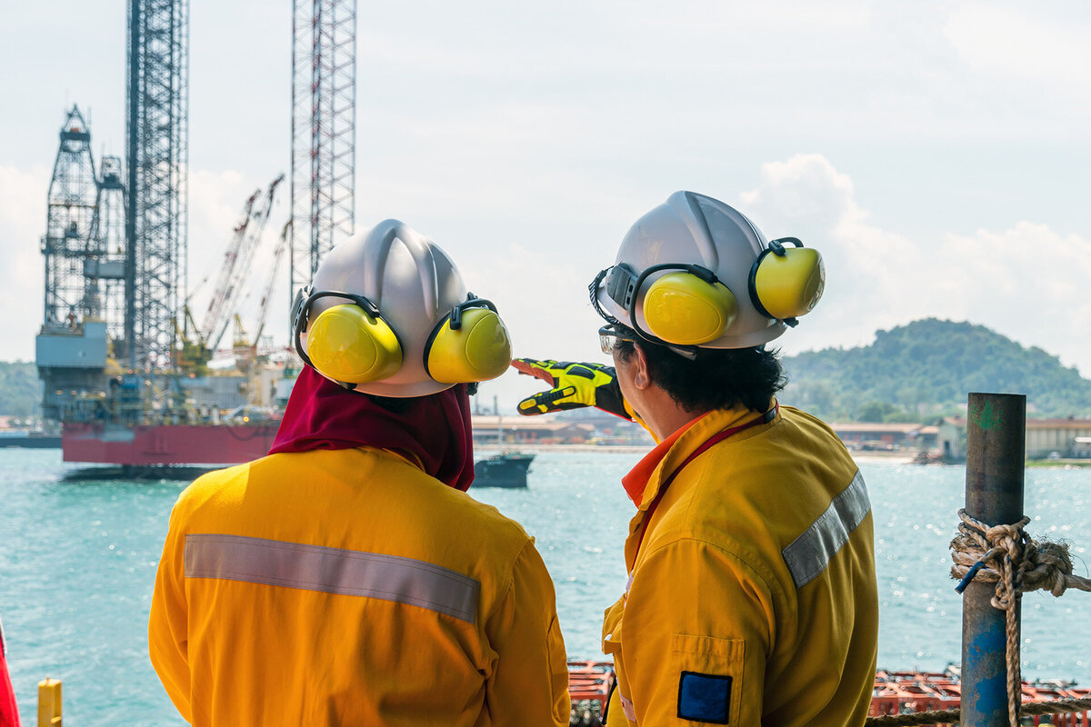 A construction supervisor giving a briefing to a fellow worker during mobilisation of a work barge at a port
