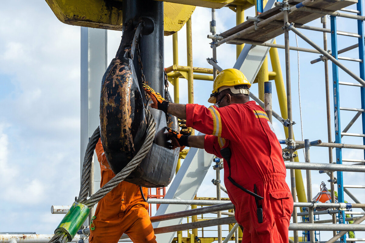 Offshore workers performing inspection to a crane hook and rigging arrangement prior to heavy lift