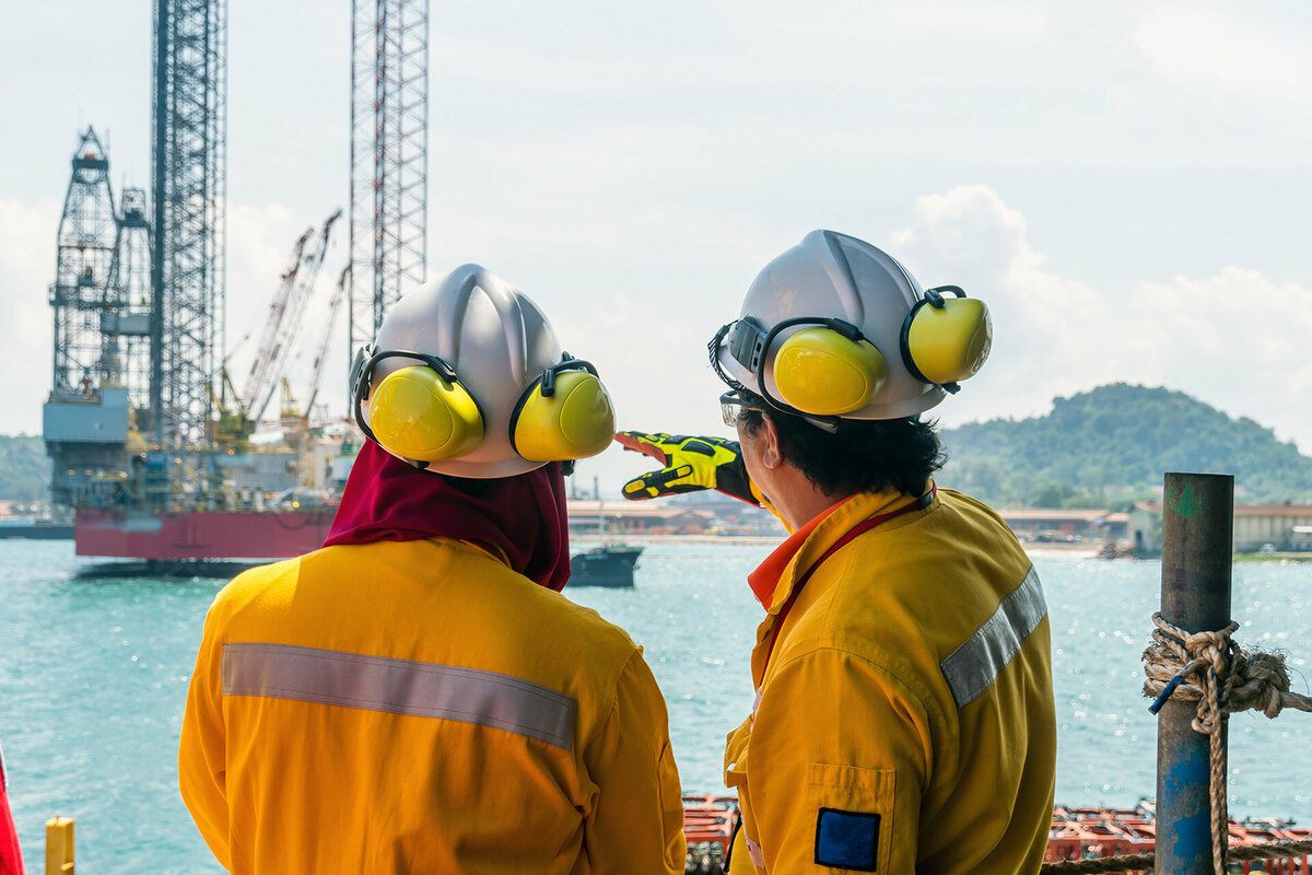 A construction supervisor giving a briefing to a fellow worker during mobilisation of a work barge at a port