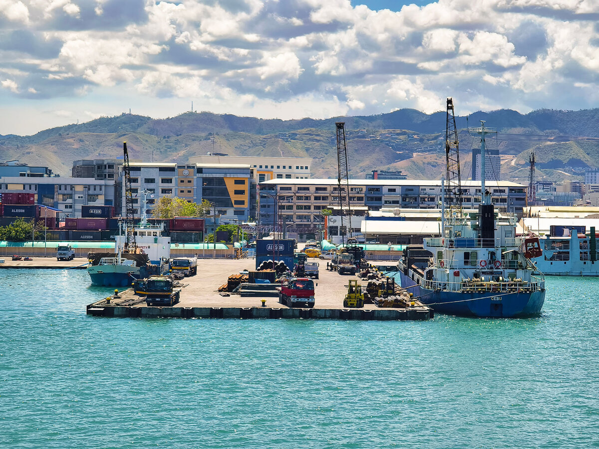 One of the berths of the port of Cebu, set against the cityscape and nearby mountains.