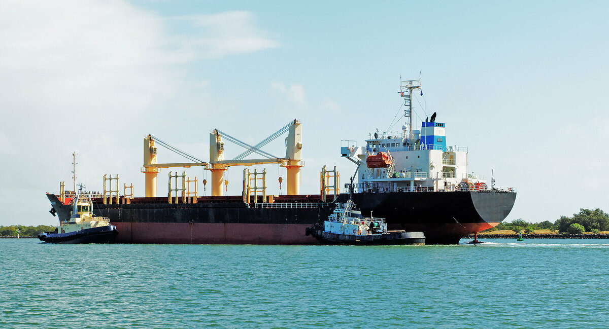 A 140 meter Bulk Carrier Ship being managed by tugboads in the Burnett River. Bundaberg, Australia.